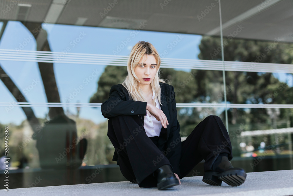 Portrait of young businesswoman with dyed blond hair sitting in front of office building Portrait of young businesswoman with dyed blond hair sitting in front of office building