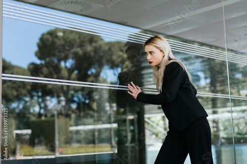 Portrait of young businesswoman wearing black pantsuit standing in front of glass pane