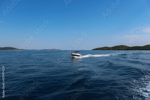 Fototapeta Naklejka Na Ścianę i Meble -  Vrgada/Croatia-July 24th,2017: Speed boat passing by our boat when returning to the coast of central Dalmatia from Vrgada island in open, adriatic waters