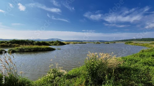 Wallpaper Mural Nature scenic of a lake, a few small islands with green grass, distant horizon with hills, blue sky with smooth clouds Torontodigital.ca