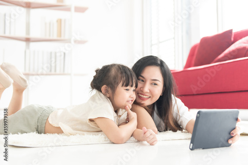 Happiness mother and daughter lie on floor of house look at tablet for entertain, family joyful together in the house