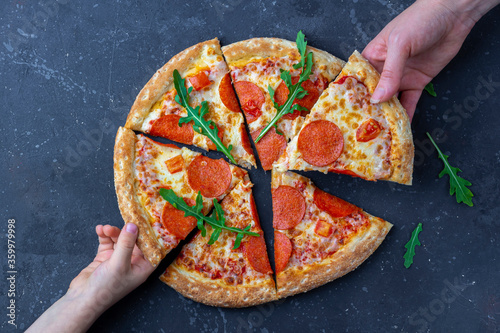 Family snack, mother and child hands taking pepperoni pizza slices. Italian traditional lunch or dinner. Fast food and street food concept. Flat lay, top view, close up