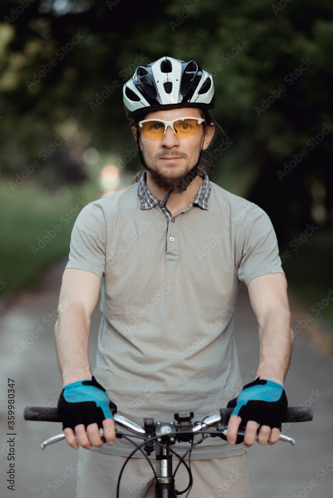 Portrait of man in a yellow sunglasses and helmet standing with bicycle on road and looking into camera. High quality Portrait of man in a yellow sunglasses and helmet standing with bicycle on road and looking into camera. High quality