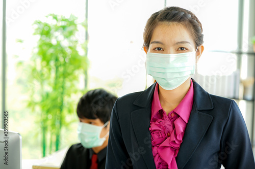 Business woman in the office and the male employee offer wearing the protective face mask safety from COVID-19 virus pandemic social distancing new normal work from home quarantine 