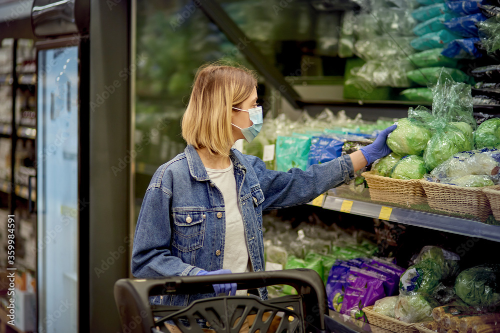 A blonde girl is standing near a shelf in fresh vegetables.