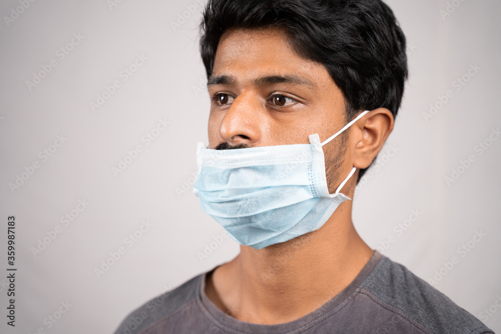 young man wearing medical mask below nose - concept showing of improper way of using face masks during coronavirus or covid-19 crisis. young man wearing medical mask below nose - concept showing of improper way of using face masks during coronavirus or covid-19 crisis.