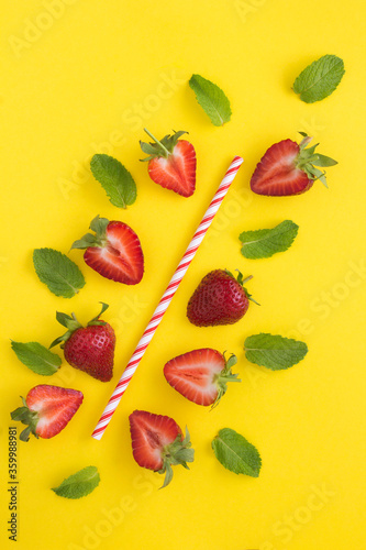 Fototapeta Naklejka Na Ścianę i Meble -  Composition with a cocktail straw, strawberries and mint  on the yellow background. Top view. Location vertical.
