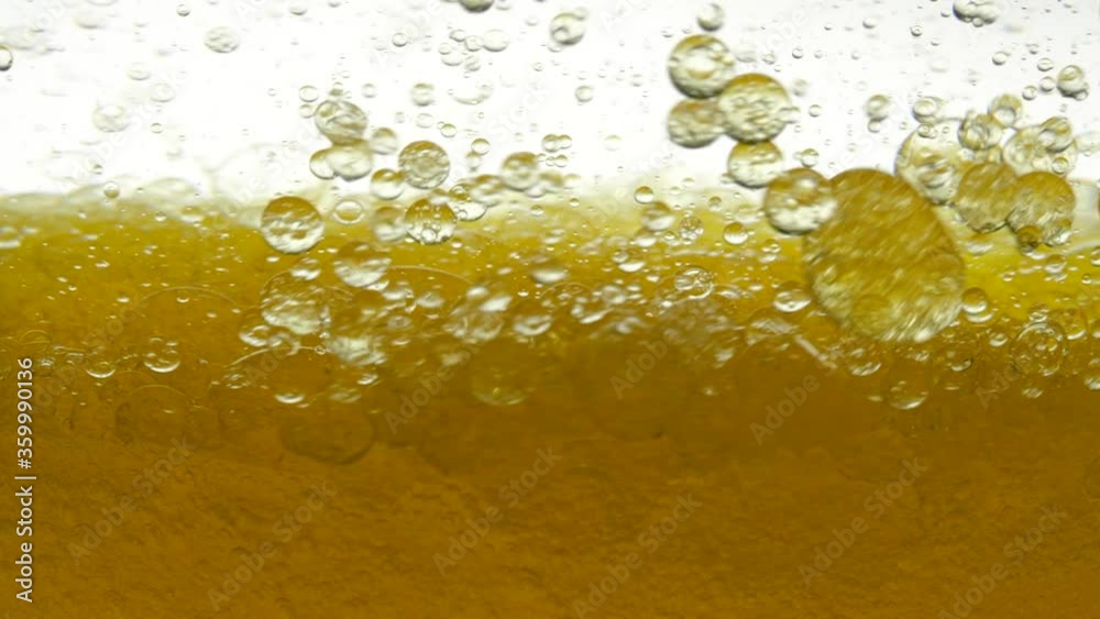 Golden and white background of poured sesame oil and black cumin oil, resulting in air bubbles and bulbs. Close shot of pouring peanut oil and golden walnut oil in container. Close-up of olive oil. Golden and white background of poured sesame oil and black cumin oil, resulting in air bubbles and bulbs. Close shot of pouring peanut oil and golden walnut oil in container. Close-up of olive oil.