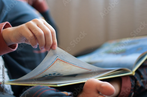 Close up of child's hand turning page of book