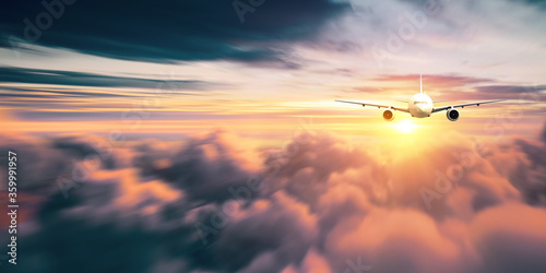 Passengers commercial airplane flying above clouds in sunset light. Concept of fast travel, holidays and business. © appledesign