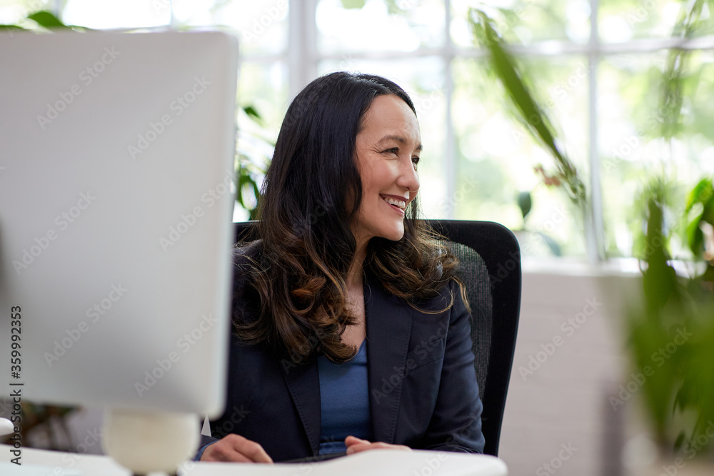 Professional business woman sitting at a desk with a computer Professional business woman sitting at a desk with a computer
