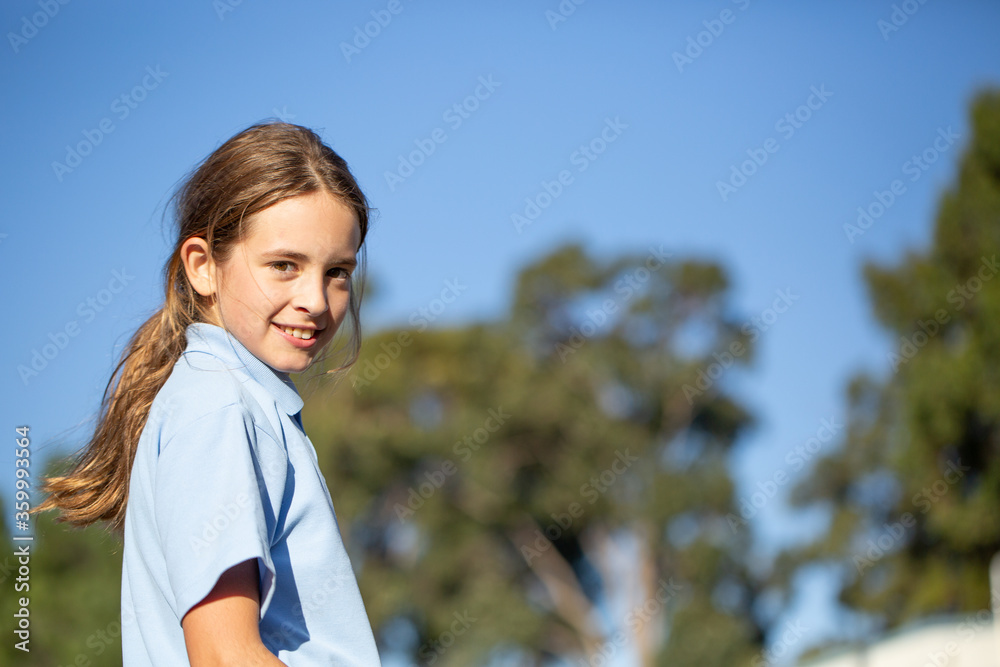 Primary school kid with ponytail looking at camera Primary school kid with ponytail looking at camera
