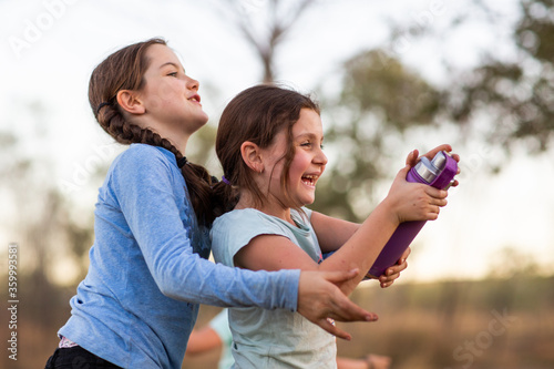 Siblings playing with water bottle outdoors photo