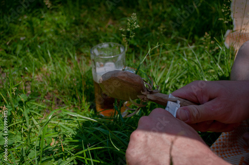 Man carving a wooden spoon. Process of making a wooden spoon. Beer mug in the background. photo