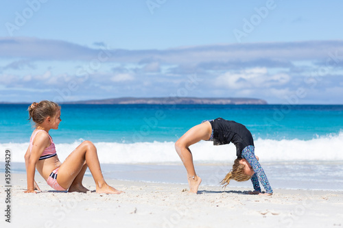 two little girls doing gymnastics on the beach