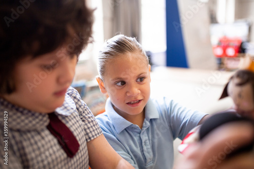 Close-up of two female students in a classroom, playing dolls