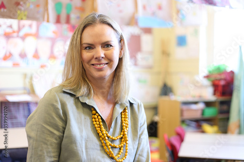 Female teacher in classroom, smiling at the camera photo