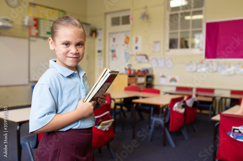 Indigenous primary school female student holding books in a classroom photo