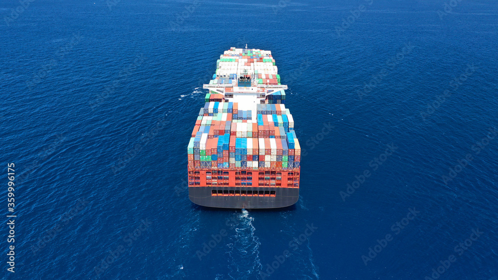 Aerial drone photo of fully loaded truck size container ship cruising in open ocean deep blue sea