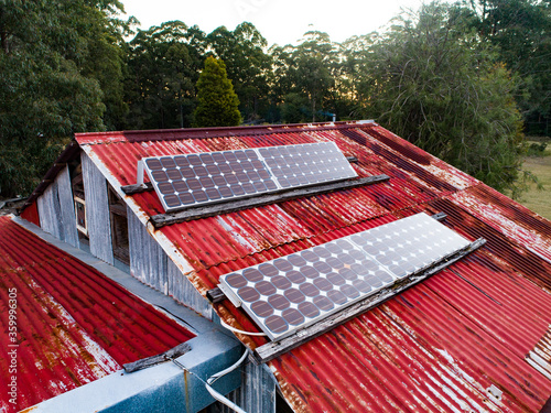 Solar panels on red tin roof of shed building on off grid farm