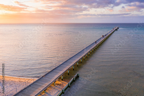 An aerial view of a long narrow jetty jutting out to sea at sunset photo