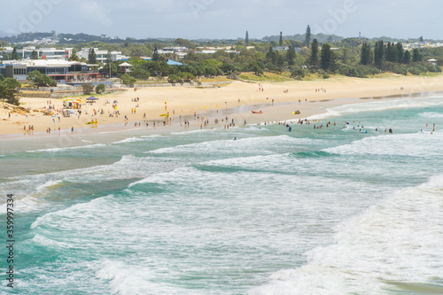 Distant view of beachgoers in the waves along a beach photo