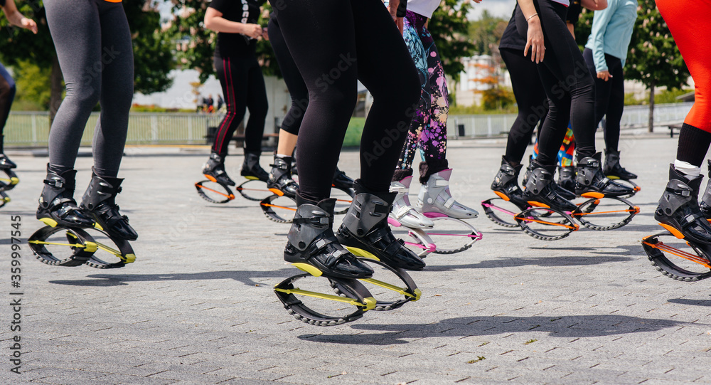 Fototapeta premium The company of young and attractive girls is engaged in aerobics in the fresh air. Healthy lifestyle. Sports shoes close-up