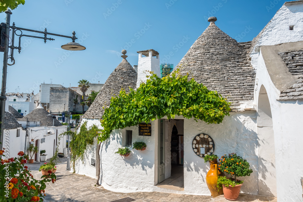 A view down a quaint, picturesque backstreet with traditional Trulli buildings in Alberobello, Italy