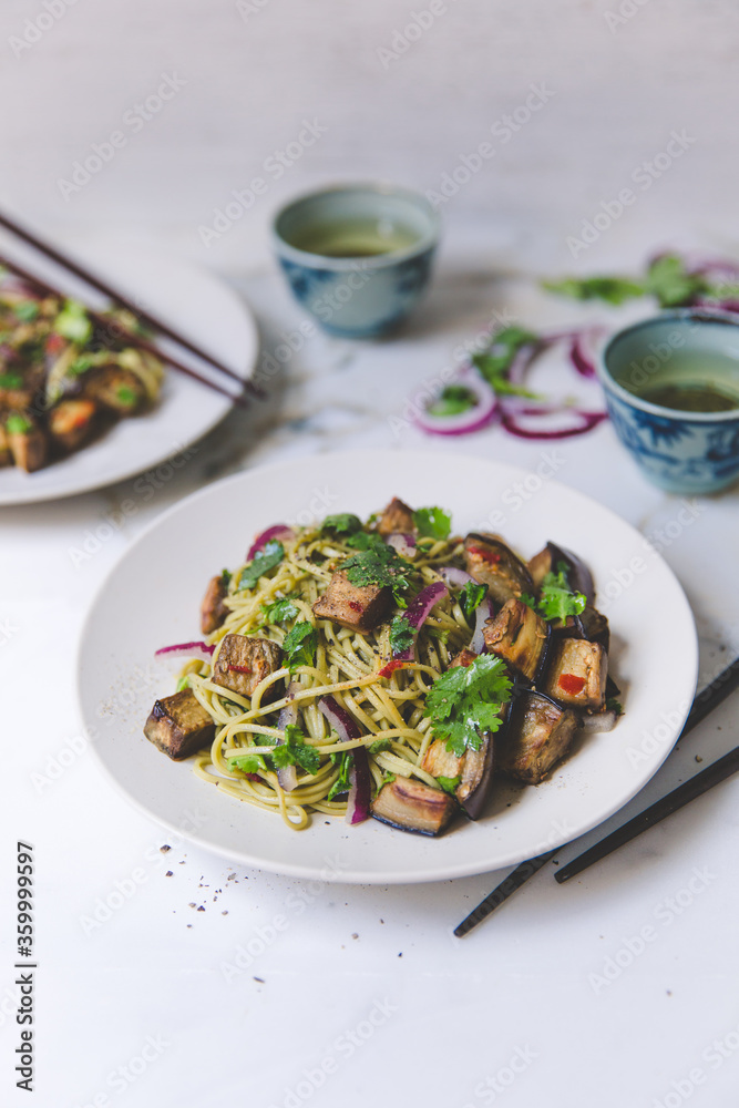 High angle of cold soba noodle, eggplant and parsley salad with green tea on white marble background High angle of cold soba noodle, eggplant and parsley salad with green tea on white marble background
