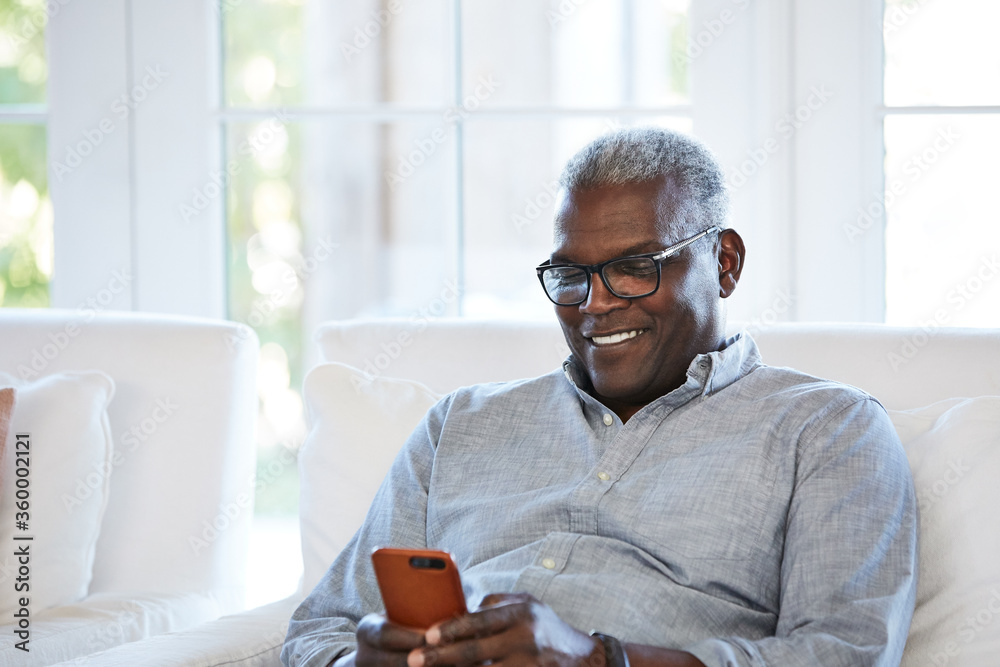 © Trinette Reed/Stocksy - African American Senior man texting on a smart phone sitting on the sofa at home © Trinette Reed/Stocksy - African American Senior man texting on a smart phone sitting on the sofa at home