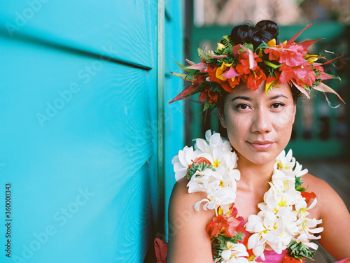 tahitian woman at turquoise plantation house in hawaii with surfboard and shower and floral crown photo