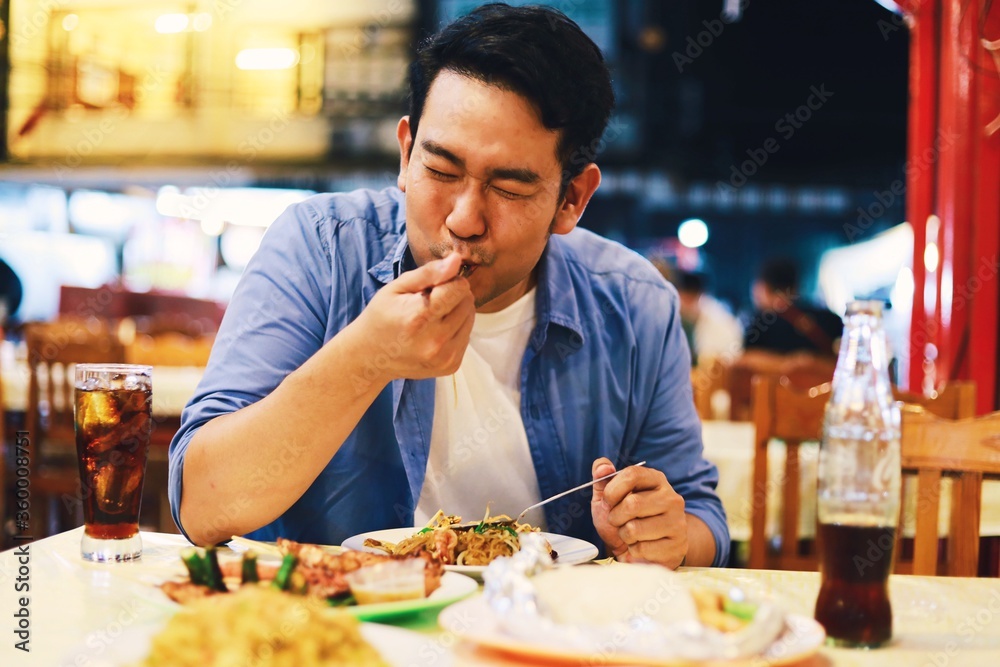 A man eating street food at night market.