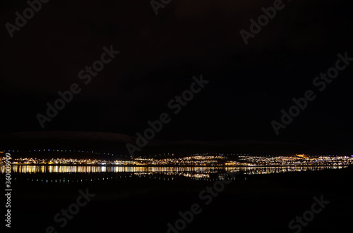 beautiful whale island in autumn darkness reflecting its light onto the fjord surface