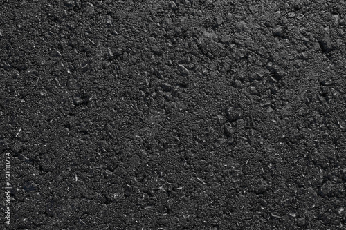 A smooth dark grey asphalt pavement texture with small rocks. Black bituminous waterproofing. Textured background.