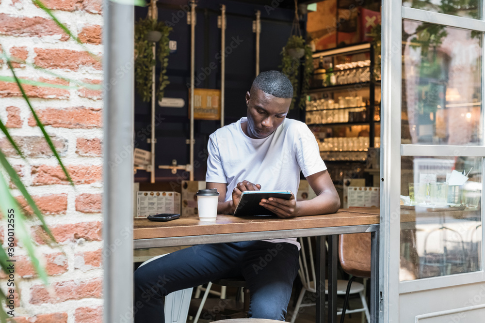 © Garage Island Crew/Stocksy - Young man working and studying at coffee shop