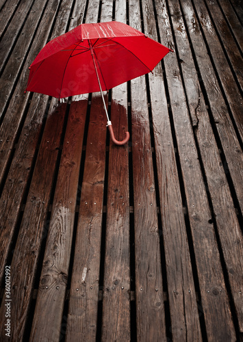 Red umbrella on wooden deck during a rainy day