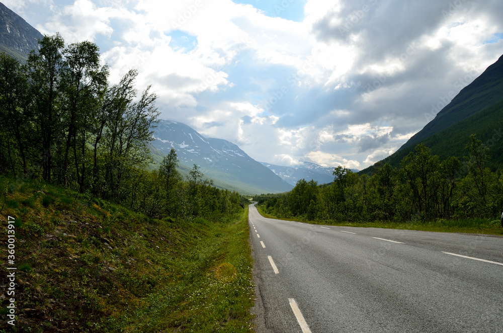 long narrow mountain road going through the arctic summer mountain and valley landscape