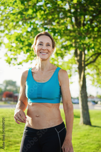 Woman sanding outside in jogging clothes.