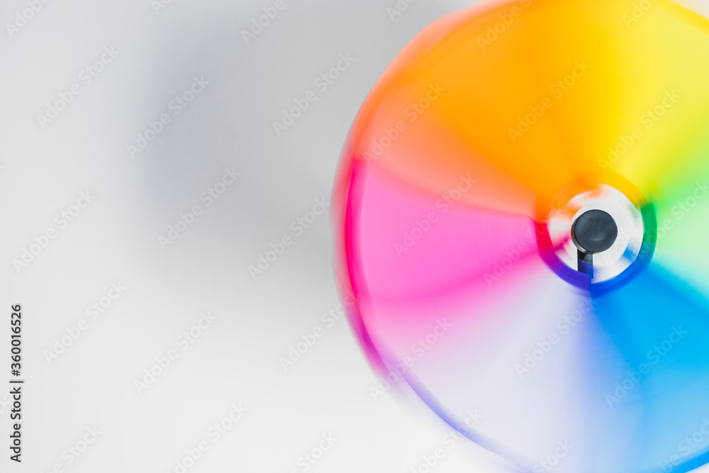 multi-colored wind toy on a white background, the blades leave a blurred trail in the form of a rainbow. LGBTQ+ sign, emblem. space for text multi-colored wind toy on a white background, the blades leave a blurred trail in the form of a rainbow. LGBTQ+ sign, emblem. space for text