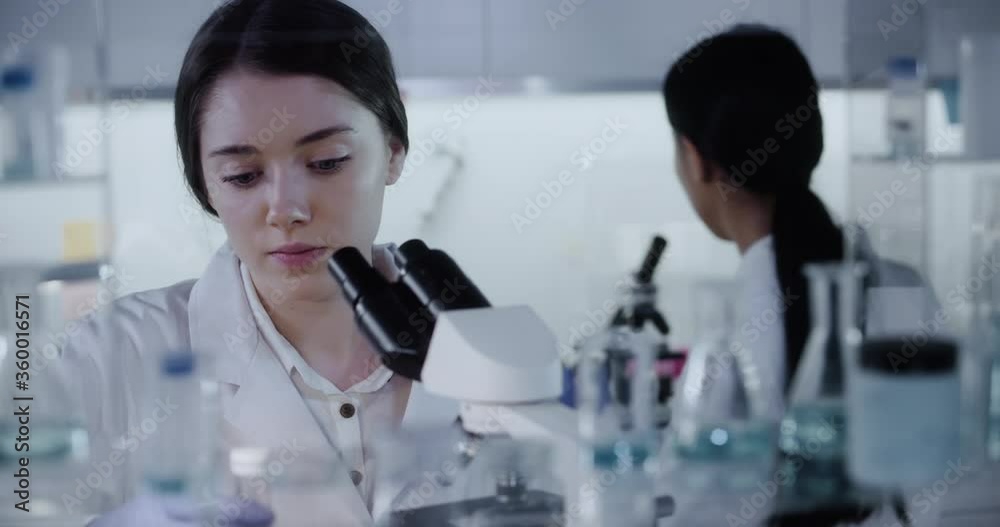 Female team working in modern laboratory. Studying genetic material with microscope. Medical sample research Female team working in modern laboratory. Studying genetic material with microscope. Medical sample research