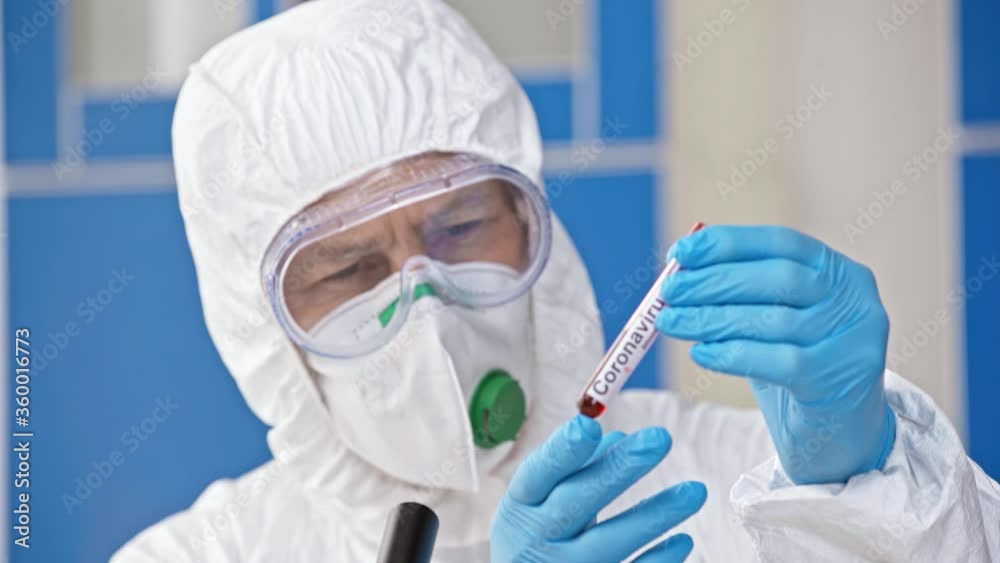 rack focus of scientist holding test tube with coronavirus lettering