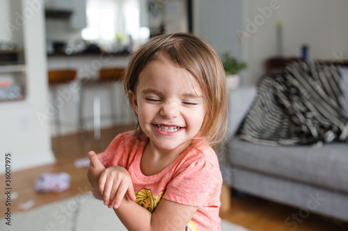 little girl smiling at camera with eyes shut
