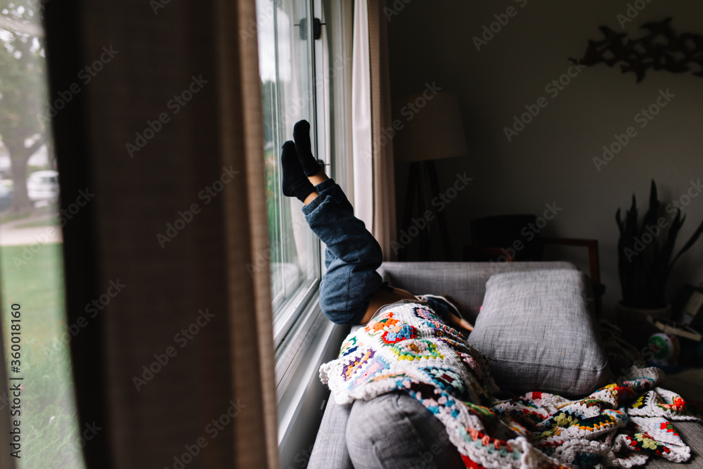 child sits upside down on couch child sits upside down on couch