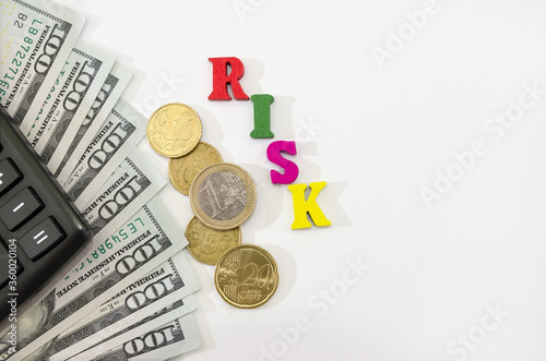 money with a calculator on a white background. The word "risk" from letters on a white background. Copy of space.