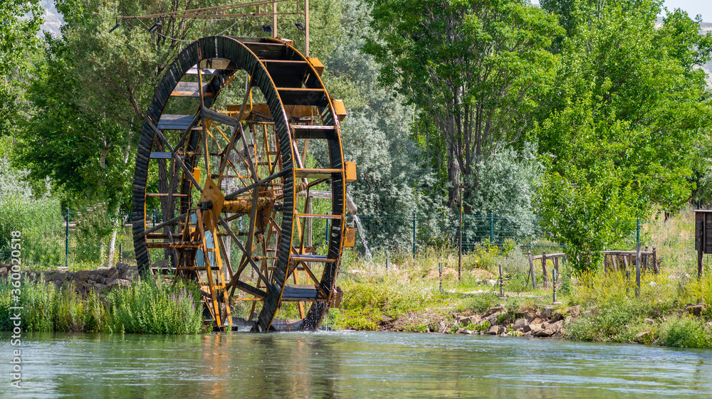 Huge water mill wheel and waterfall on river on sunny day. Sustainable energy and water power traditional machinery Huge water mill wheel and waterfall on river on sunny day. Sustainable energy and water power traditional machinery