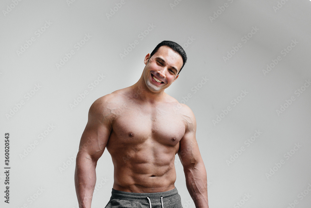 Fototapeta premium Sporty, sexy athlete smiling on a white background. Fitness