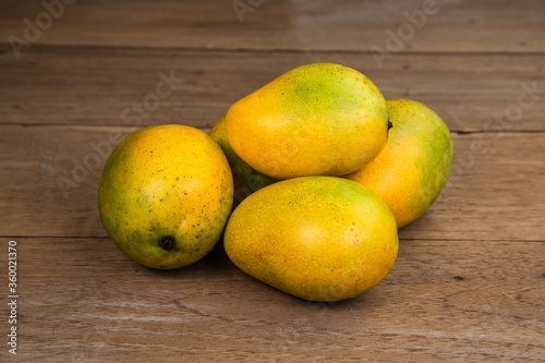 Ripe mango on wooden table. Tropical fruit. Group of fresh mango. Ripe yellow mangoes on wooden background