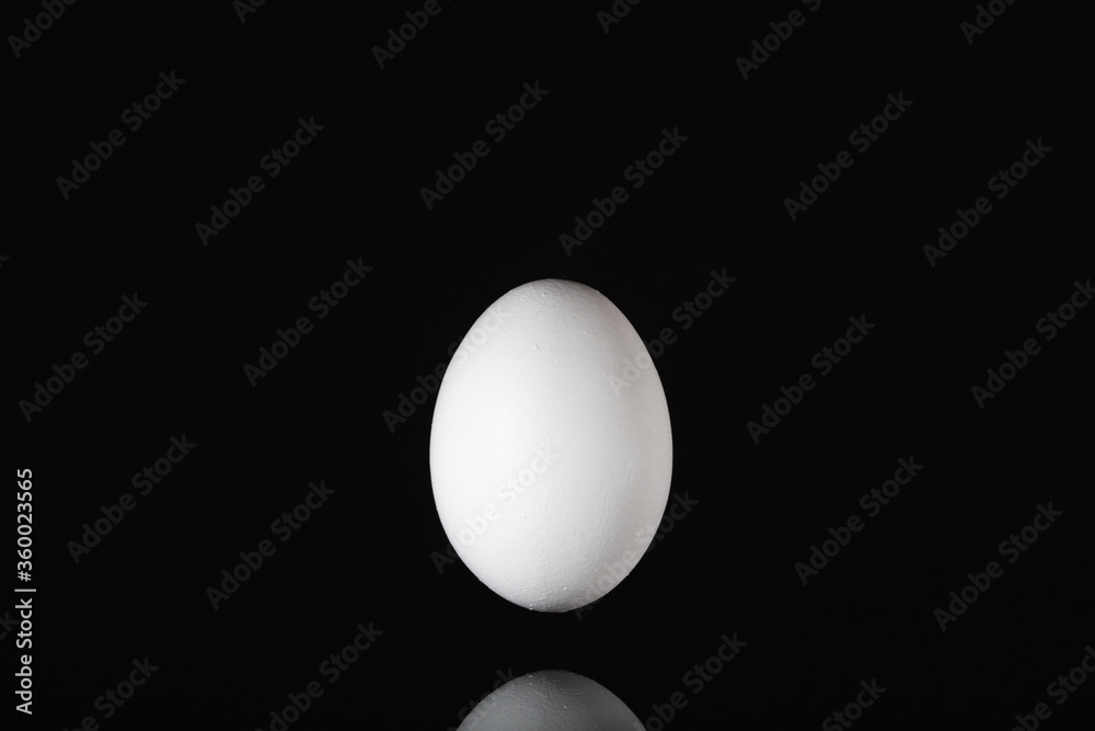 White egg levitating over a black glass table White egg levitating over a black glass table