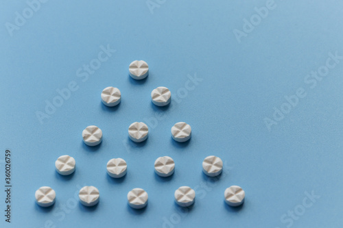 Round tablets of white color are laid out in the form of a triangle on a blue background. Close up © Евгения Якименко