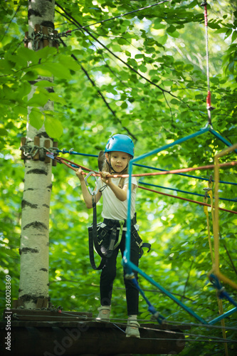 Extreme rope adventure in the forest - a little girl about to walk on the rope bridge